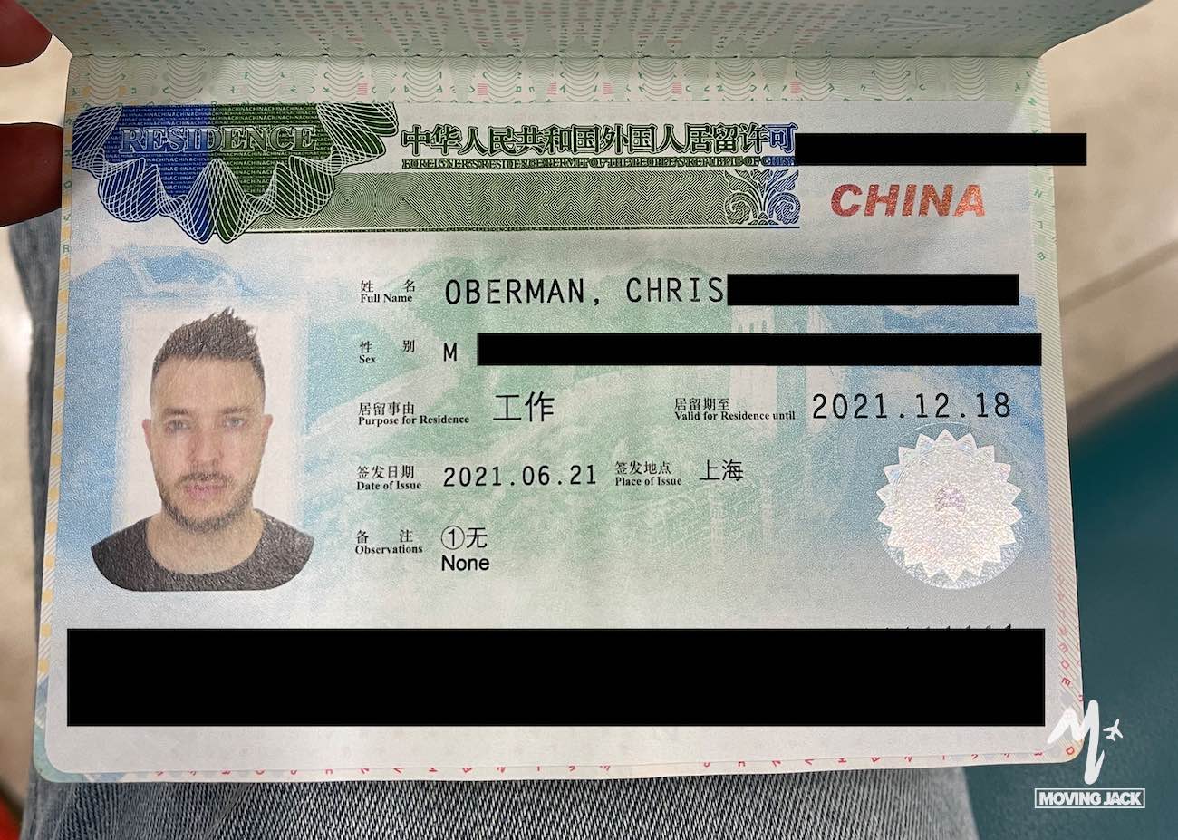 Een Chinese visumpagina in een paspoort toont een foto van een man, persoonlijke gegevens en visuminformatie – ideaal voor iedereen die overweegt als buitenlander in Shanghai te wonen. Verschillende gedeeltes zijn zwart gemaakt voor privacydoeleinden, met het Moving Jack-logo in de rechterbenedenhoek. -Copyright-moving-jack.com