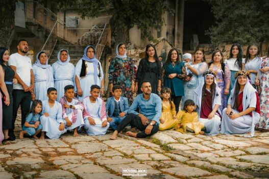 Geheimen van de Lalish-tempel: de verborgen cultuur van de Yazidi's 25 Een diverse groep mannen, vrouwen en kinderen poseert buiten op het stenen plaveisel van lalish. Sommigen dragen traditionele kleding in felle kleuren, ter ere van het culturele erfgoed te midden van de serene achtergrond. -copyright-moving-jack. Com