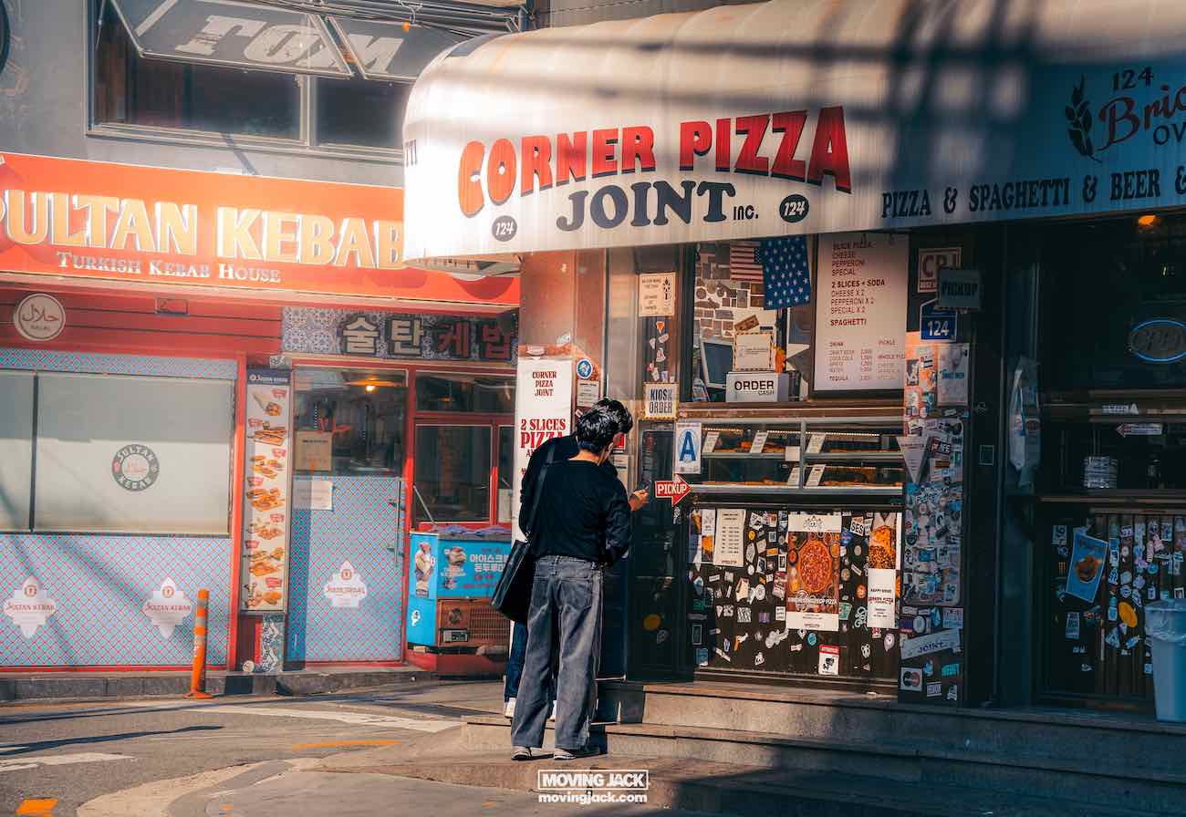Visiting seoul: 12 fascinating first impressions you'll spot instantly 11 seoul A person stands in front of corner pizza joint, with sultan kebab house next door, reminiscent of a bustling corner you might find in seoul. Sunlight casts gentle shadows on the street. -copyright-moving-jack. Com