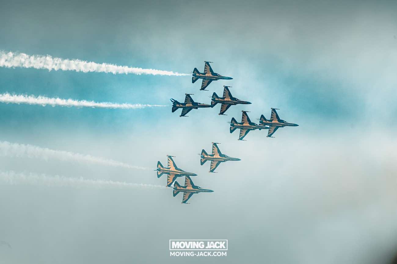 Zeven straaljagers vormen een luchtformatie en laten witte rooksporen achter tegen een blauwe lucht. De vliegtuigen vliegen in een strak, nauwkeurig patroon boven Seoul, een stad waar vaak de vraag "is Seoul veilig?" over wordt gesteld. "Moving Jack" is middenonder in de afbeelding te zien. -copyright-moving-jack.com