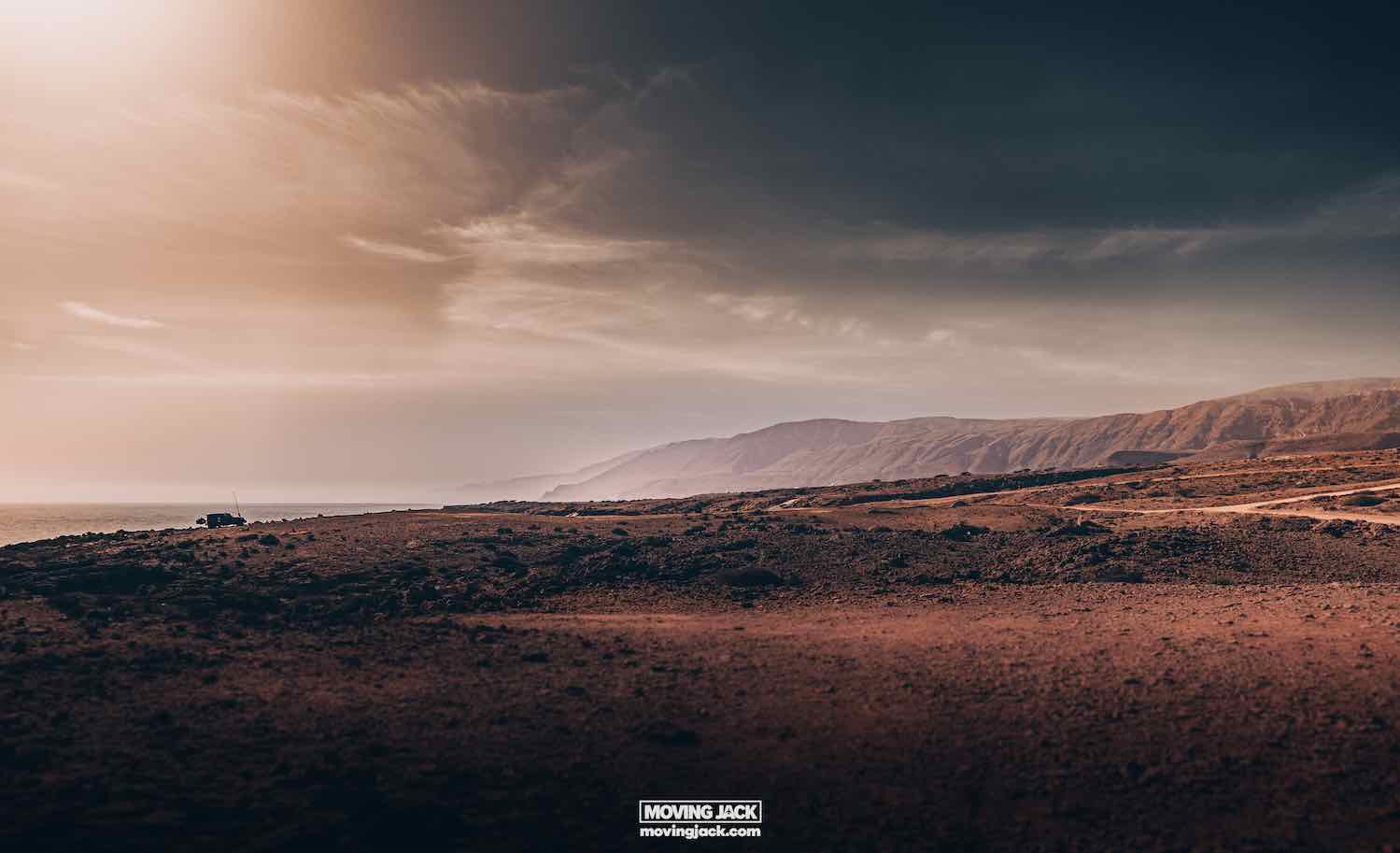What to see in oman: the 12 sights that will make you love it 8 what to see in oman A vast, desolate landscape under a cloudy sky with distant mountains and a dirt path running through the barren terrain. -copyright-moving-jack. Com
