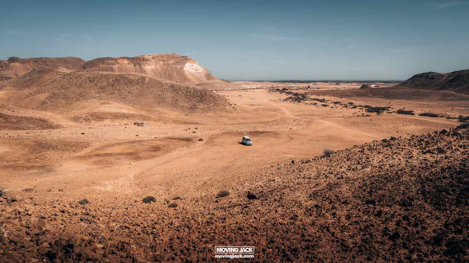What to see in oman: the 12 sights that will make you love it 11 what to see in oman A lone vehicle travels through a vast, rocky desert landscape under a clear blue sky. Hills and sparse vegetation are visible in the distance. -copyright-moving-jack. Com