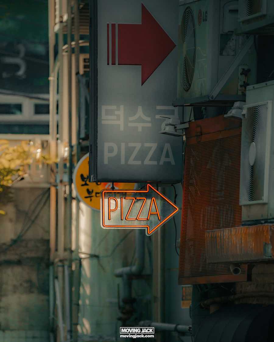 Waar te verblijven in Seoul: beste hotels + reisgids voor gebieden 17 waar te verblijven in Seoul Een levendig neonbord met een rode pijl en de tekst "pizza" siert de buitenkant van het gebouw, wat een hint geeft naar waar je in Seoul kunt verblijven voor de beste pizza. Een ander bord met Koreaanse tekst met "pizza" leidt je naar dit culinaire rijk, waar airconditioningunits zelfs op sissende zomerdagen voor comfort zorgen. -copyright-moving-jack. Com
