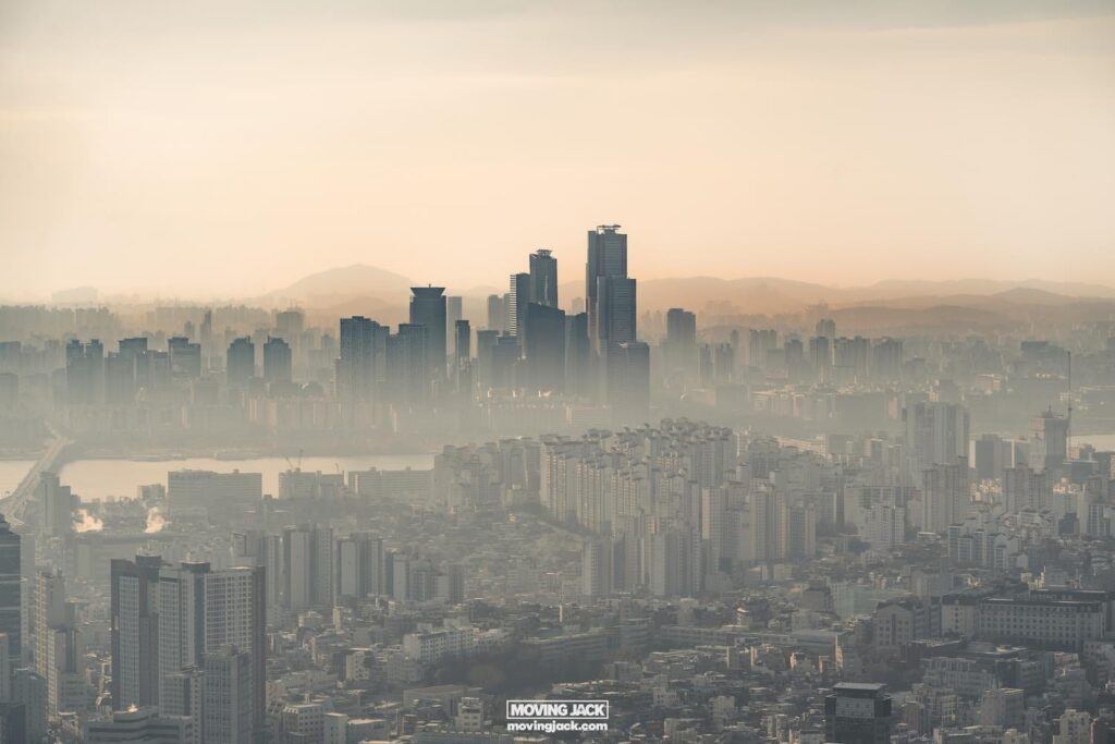 Waar te verblijven in Seoul: beste hotels + reisgids voor gebieden 21 waar te verblijven in Seoul Luchtfoto van het stadsbeeld van Seoul met hoge wolkenkrabbers en verre bergen onder een wazige lucht, die een glimp biedt van waar u kunt verblijven in deze bruisende metropool. -copyright-moving-jack. Com