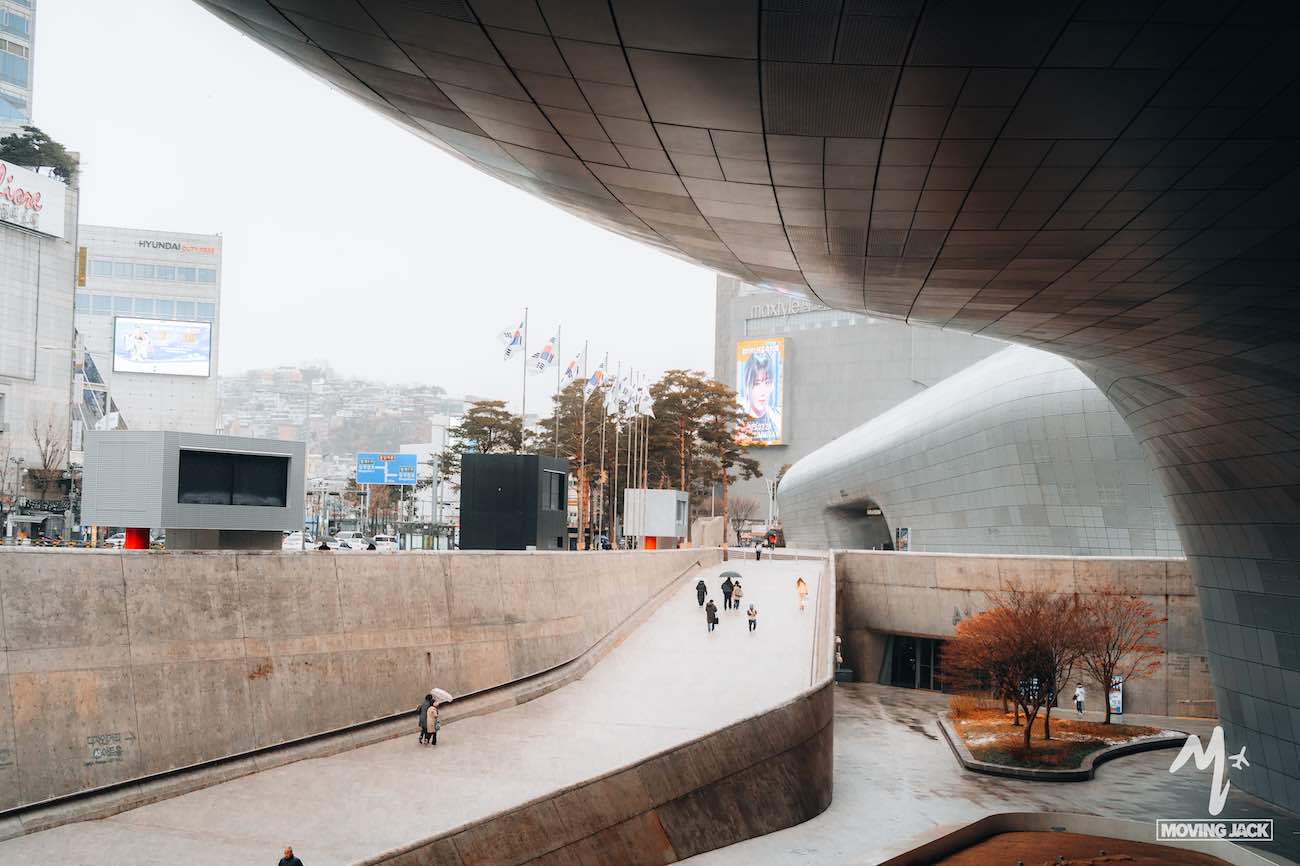 Gebogen moderne architectuur met mensen die over een brede helling lopen in een stedelijke, winterse omgeving.