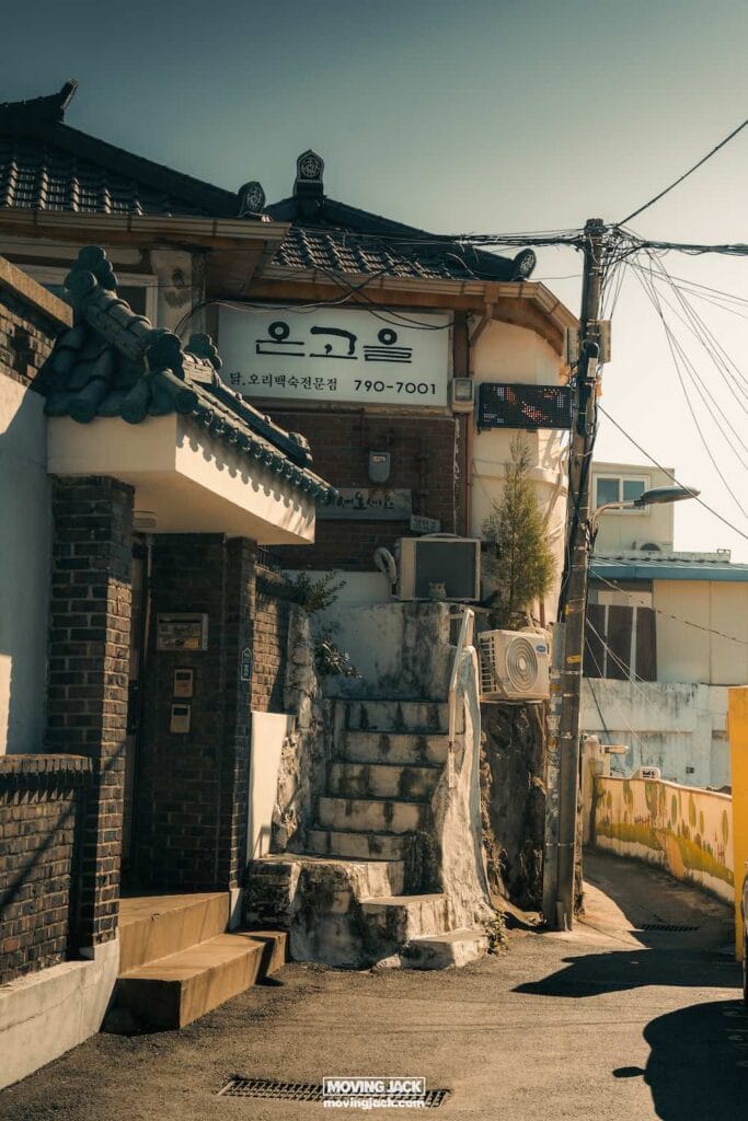 Reisroute Itaewon 2025: de beste eetgelegenheden, drankjes en uitgaansgelegenheden 14 Itaewon Smalle straat in de oude wijk Itaewon, omzoomd met bakstenen en stenen gebouwen, elektrische draden kruisend boven je hoofd tegen een heldere hemel. -copyright-moving-jack. Com