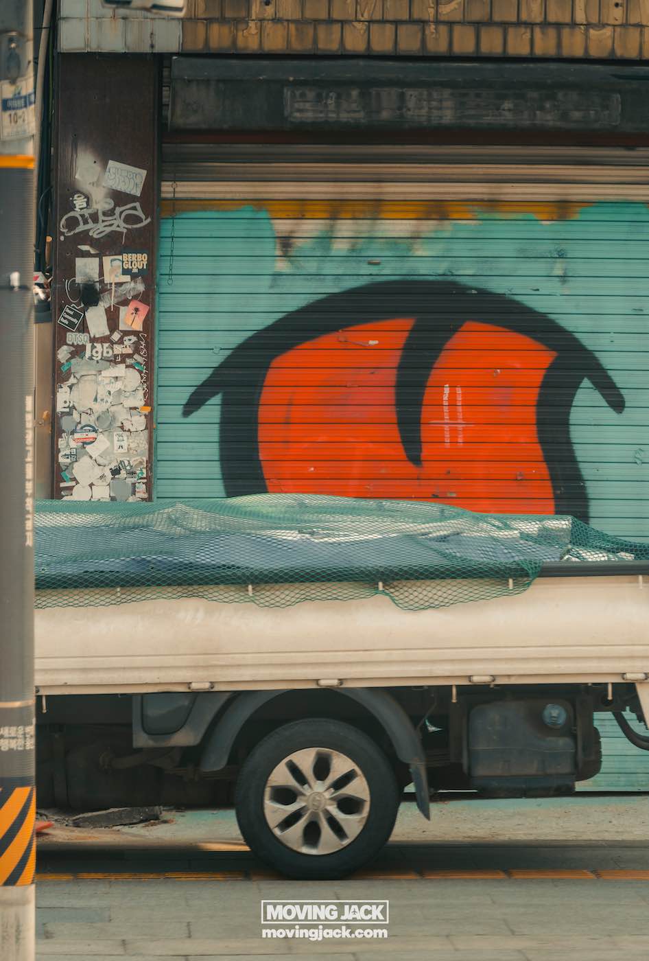 Reisroute Itaewon 2025: de beste eetgelegenheden, drankjes en uitgaansgelegenheden 35 Itaewon Een witte vrachtwagen staat geparkeerd voor een met graffiti bedekt luik in Itaewon. Het luik heeft een opvallend rood-zwart abstract ontwerp, terwijl links een met stickers versierde elektriciteitspaal staat. -copyright-moving-jack.com