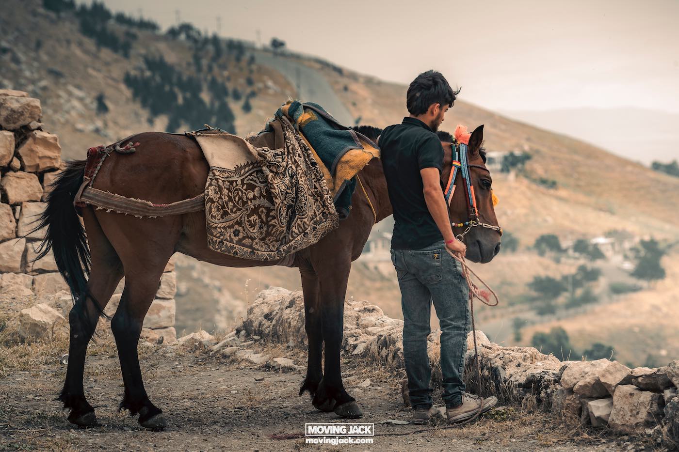 Visiting erbil & iraq for the first time: expert guide + tips 18 first time A man in a black shirt, clearly a first-timer on this rocky pathway, stands beside his saddled donkey against a backdrop of rolling hills. -copyright-moving-jack. Com
