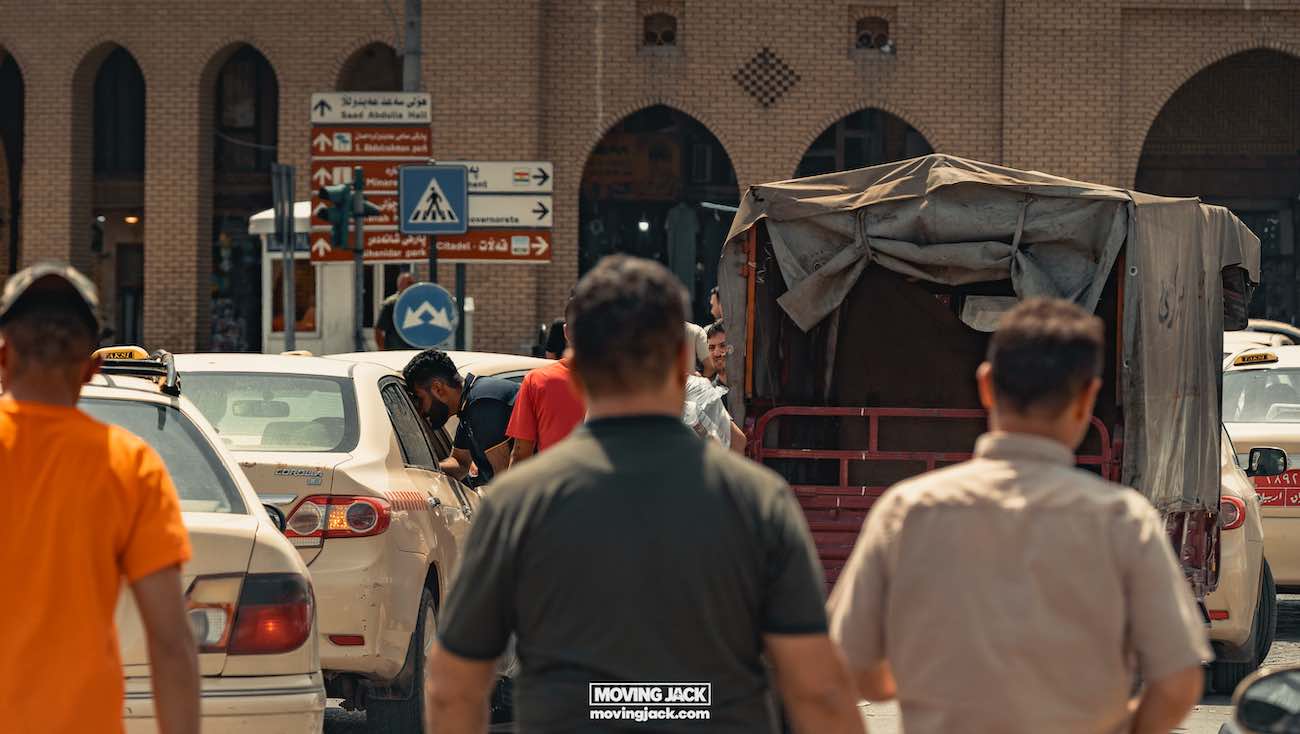 Visiting erbil & iraq for the first time: expert guide + tips 15 first time People walk down a busy street for the first time, with cars and a covered truck in the background, under clear skies. -copyright-moving-jack. Com