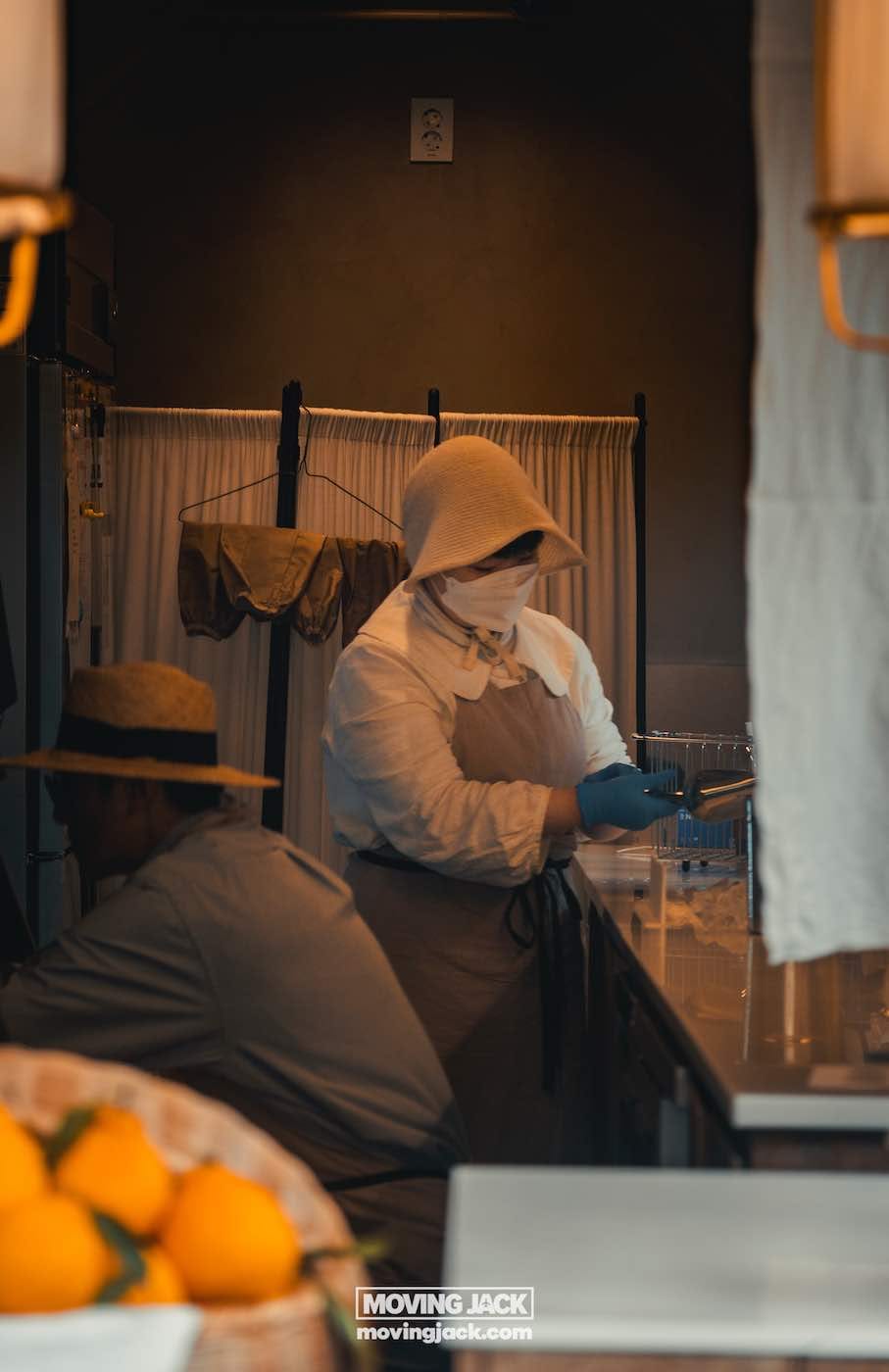 Ikseon dong hanok dorpsroute: waar te eten, drinken en verblijven 13 ikseon dong In een slecht verlichte ikseon dong-keuken dragen twee personen hoeden en beschermende kleding. De een staat de afwas te doen, terwijl de ander ernaast hurkt, met een verse stapel sinaasappels op de voorgrond. -copyright-moving-jack. Com