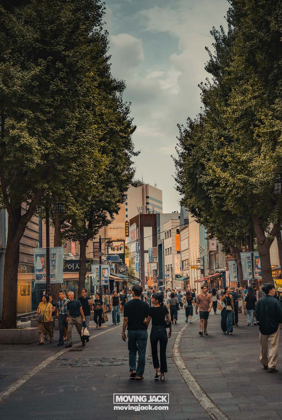 Ikseon dong hanok dorpsroute: waar te eten, drinken en verblijven 20 ikseon dong Mensen lopen langs een drukke stadsstraat met bomen en moderne gebouwen onder een bewolkte lucht. -copyright-moving-jack. Com