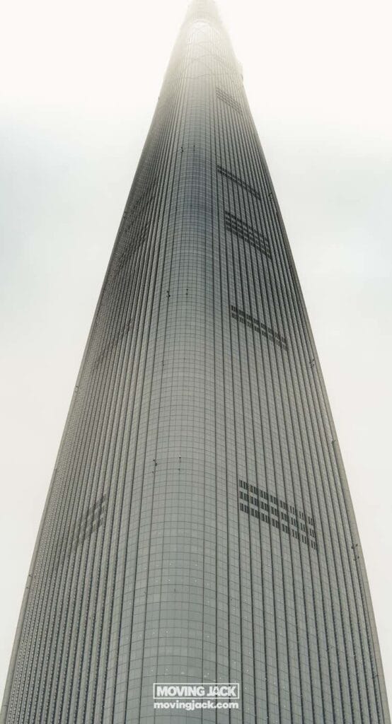 Wat te doen in Seoul: 13 unieke dingen om te doen + wat je beter kunt overslaan! 39 dingen om te doen in Seoul Omhoogkijkend naar een hoge, moderne wolkenkrabber gehuld in mist. De gevel van het gebouw heeft verticale lijnen en een paar kleine ramen. -copyright-moving-jack. Com