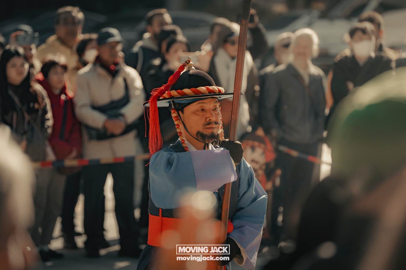 Gyeongbokgung paleis Seoul ultieme gids + wandelvideo 12 Gyeongbokgung Te midden van een drukke menigte staat een persoon in traditionele kledij klaar, met een speer in de hand - een levendige momentopname van de cultuur die je kunt ervaren tijdens het verkennen van Seoul met een beperkt budget. -copyright-moving-jack. Com