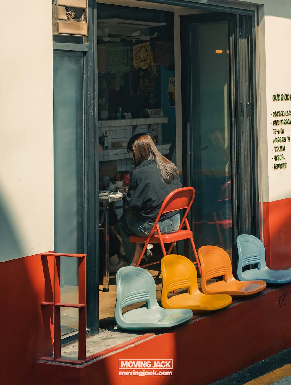 Reisroute Itaewon 2025: de beste eetgelegenheden, drankjes en uitgaansgelegenheden 7 Itaewon Een persoon zit in een klein café, zichtbaar door een glazen schuifdeur. Buiten staan drie kleurrijke stoelen opgesteld langs een richel. -copyright-moving-jack.com