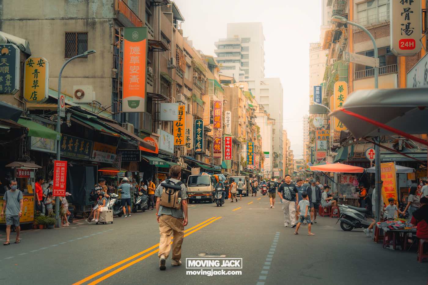 Reiscitaten: 120 unieke Instagram-bijschriften + generator voor 10 reiscitaten Drukke stadsstraat in Taipei, Taiwan, met aan beide kanten wandelende mensen, straatverkopers en winkels; kleurrijke borden met Chinese karakters zorgen voor een levendige reissfeer. -copyright-moving-jack.com