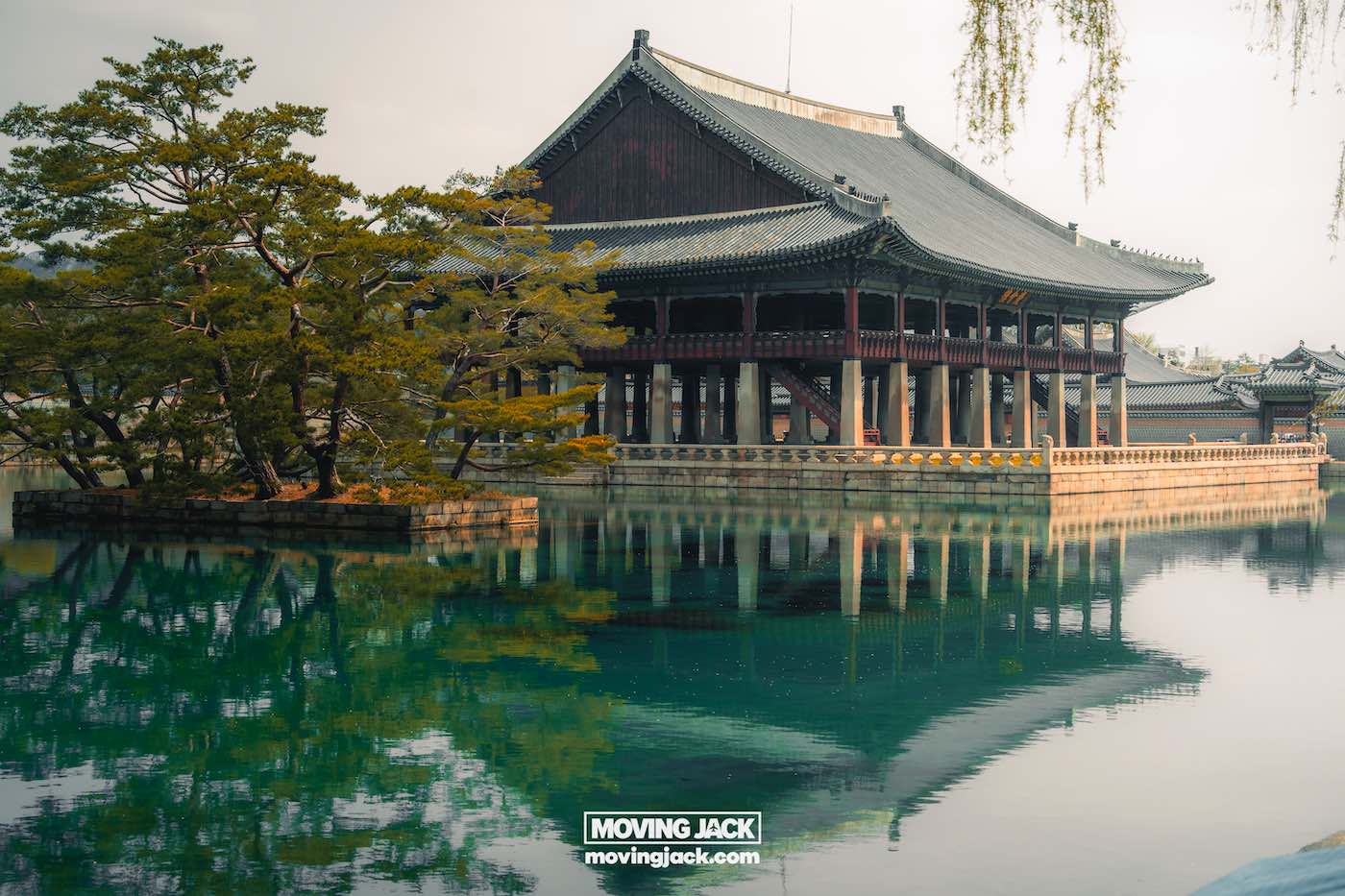 Gyeongbokgung paleis Seoul ultieme gids + wandelvideo 6 Gyeongbokgung Een traditioneel Koreaans paviljoen in Gyeongbokgung staat op palen boven een spiegelende vijver, omgeven door bomen en een mistige atmosfeer. -copyright-moving-jack.com