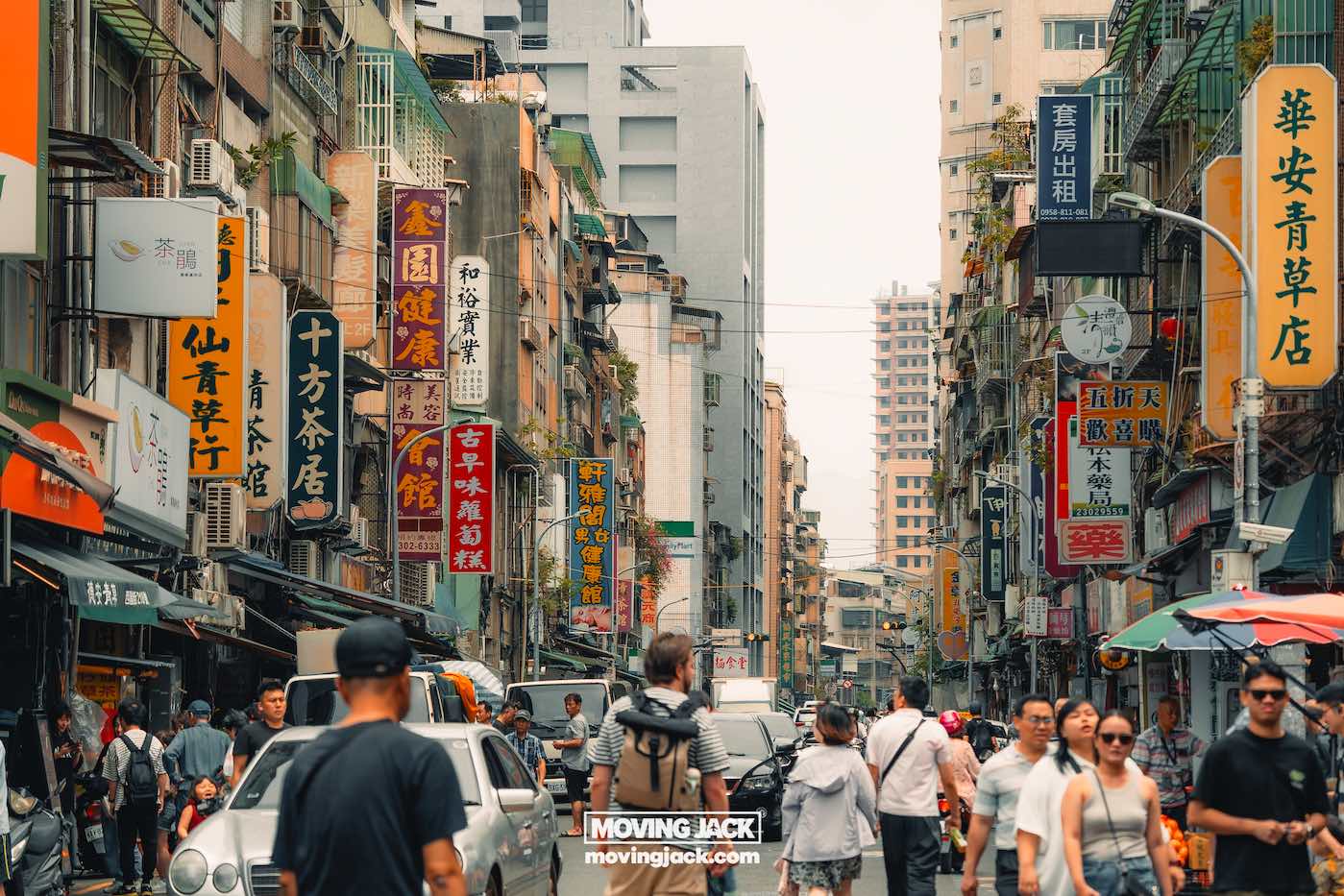 Reiscitaten: 120 unieke Instagram-bijschriften + generator voor 5 reiscitaten Drukke stadsstraat met gebouwen met kleurrijke Chinese borden, vol voetgangers en voertuigen – een stedelijk tafereel dat talloze reiscitaten zou kunnen inspireren. -copyright-moving-jack.com