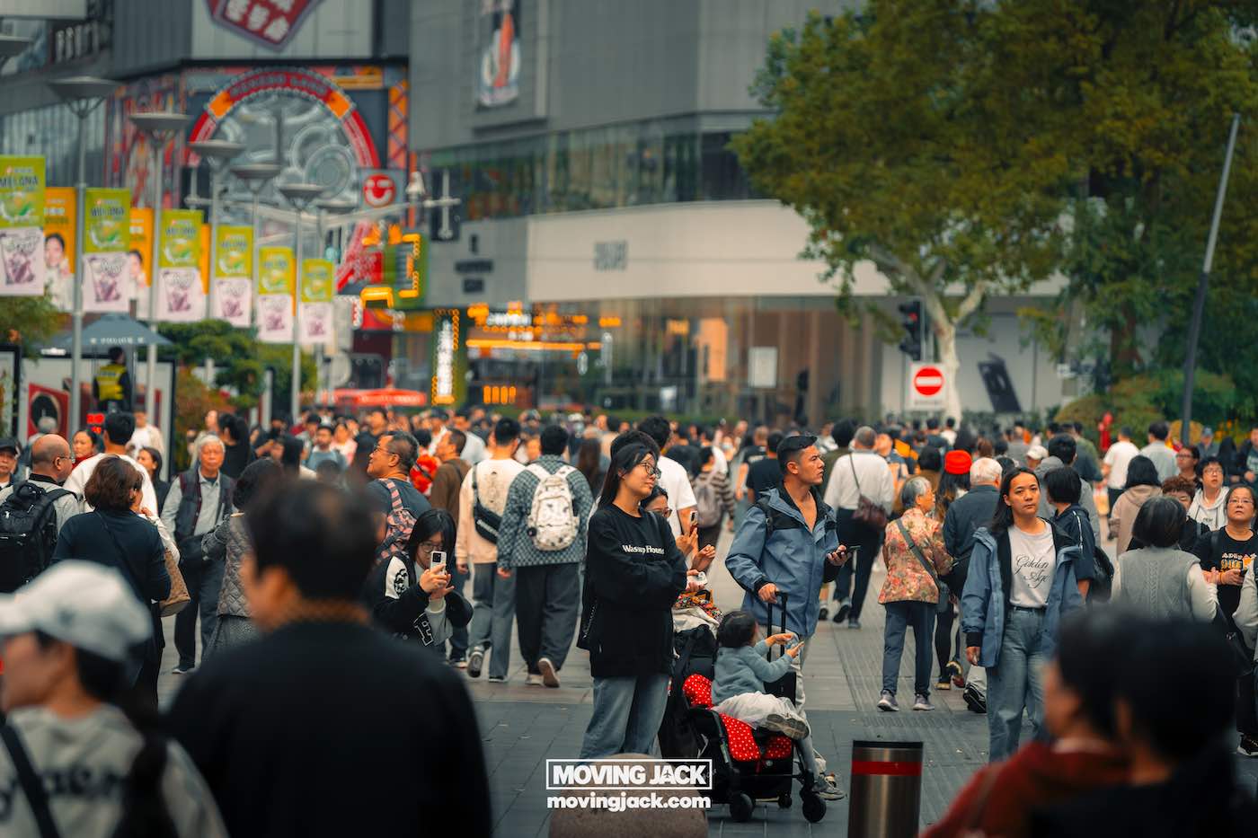 Waar te verblijven in Shanghai: 5 leukste gebieden + beste hotels 6 waar te verblijven in Shanghai Een drukke stadsstraat vol mensen die in verschillende richtingen lopen, omringd door winkels, borden en bomen – een levendig tafereel, typisch voor wie op zoek is naar een slaapplek in Shanghai. -copyright-moving-jack.com