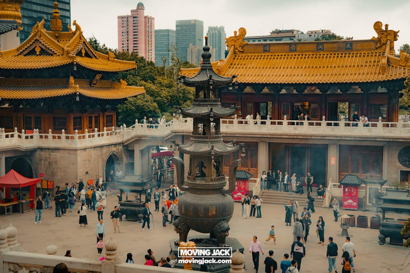 Waar te verblijven in Shanghai: 5 leukste wijken + beste hotels 21 waar te verblijven in Shanghai Mensen bezoeken een traditionele tempelbinnenplaats met sierlijke gouden daken en wierookbranders, afgezet tegen moderne stadsgebouwen – een must-see voor iedereen die op zoek is naar een verblijfplaats in Shanghai. -copyright-moving-jack.com