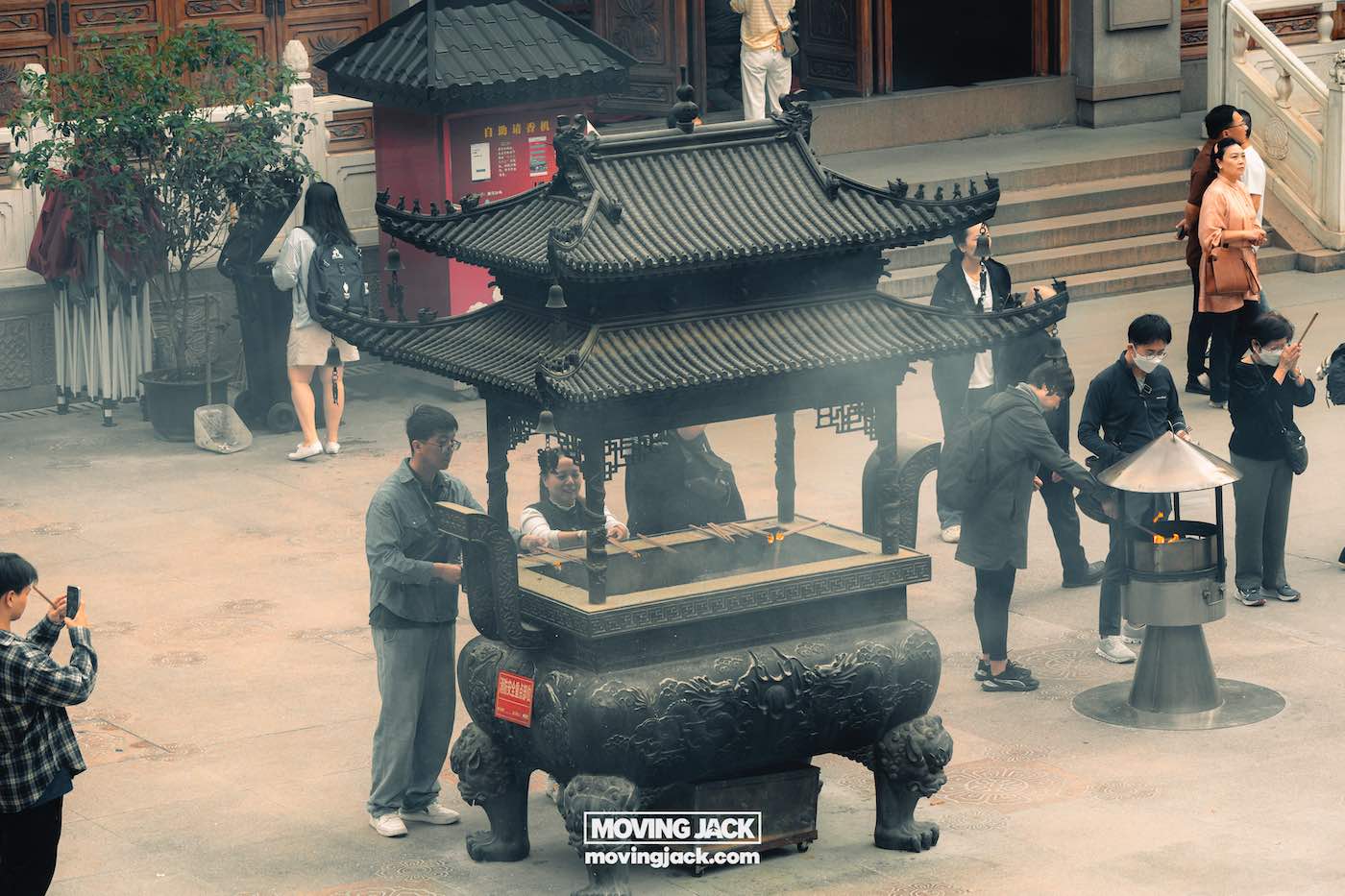 57 things to do in shanghai: the ultimate handbook 13 things to do in shanghai People gather around a large incense burner at jing'an temple showing spiritual things to do in shanghai, with smoke rising as visitors pray and take photos, stairs and donation box visible in the background. -copyright-moving-jack. Com