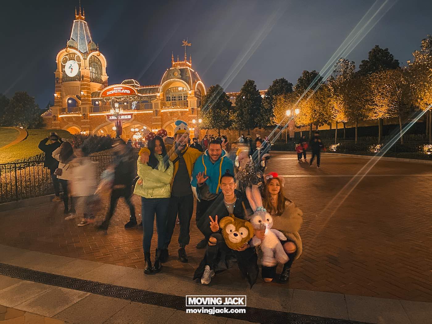 Waar te verblijven in Shanghai: 5 leukste wijken + beste hotels 33 waar te verblijven in Shanghai Een groep van vijf mensen poseert 's avonds voor een foto voor een felverlichte ingang van Disneyland. Ze leggen herinneringen vast terwijl ze de opties voor overnachtingen in Shanghai verkennen, terwijl anderen op de achtergrond rondslenteren. -copyright-moving-jack.com