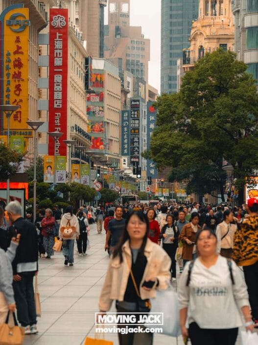 Where to stay in shanghai: 5 most fun areas + best hotels 43 avatar mountains A busy urban street in shanghai with many people walking, tall buildings lined with colorful signs, and trees along the walkway—perfect for exploring while deciding where to stay in shanghai during the daytime. -copyright-moving-jack. Com