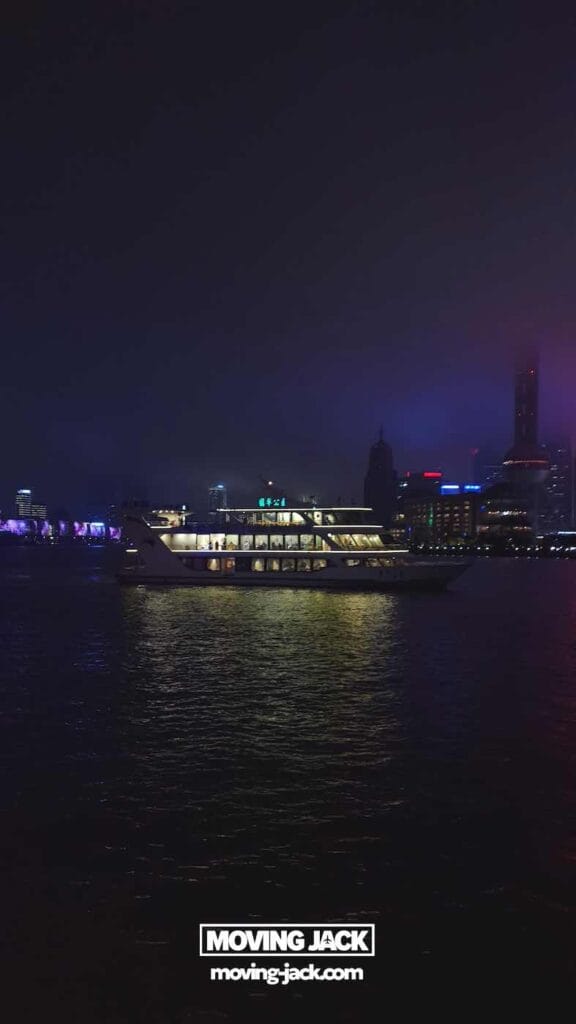 Shanghai 's nachts: beste handboek voor het nachtleven (2025) 14 Shanghai 's nachts Een verlichte boot vaart 's nachts over de rivier in Shanghai, met stadsgebouwen en neonlichten op de achtergrond. Onderaan staat het logo van "Moving Jack". -copyright-moving-jack.com