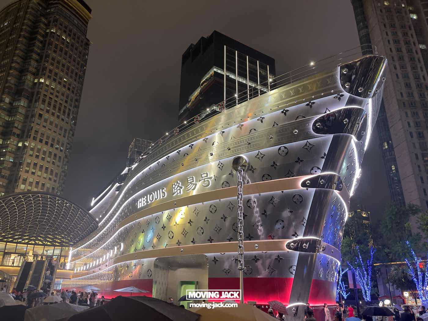 Shanghai 's nachts: beste handboek voor het nachtleven (2025) 19 Shanghai 's nachts Een groot gebouw, ontworpen om op een schip te lijken, versierd met het merk Louis Vuitton, wordt 's nachts verlicht in Shanghai, te midden van een stedelijke omgeving met hoge gebouwen in de buurt. -copyright-moving-jack.com