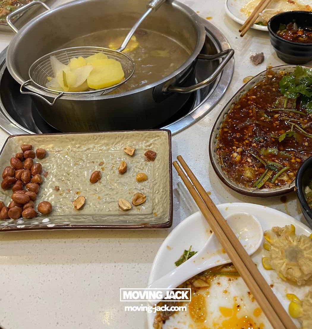 57 things to do in shanghai: the ultimate handbook 27 things to do in shanghai A hot pot meal in progress at haidilao with steam rising from the pot, surrounded by plates of peanuts, raw meat, vegetables, and used dishes on a round table—showing social dining things to do in shanghai that create unforgettable experiences with friends.