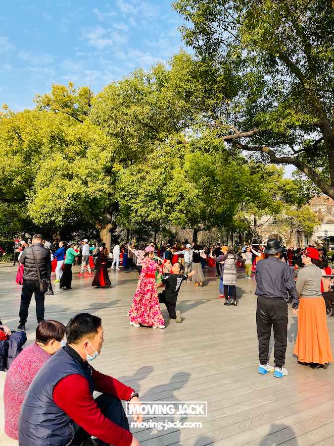 57 things to do in shanghai: the ultimate handbook 30 things to do in shanghai A group of people in colorful clothes dance and gather outdoors on a sunny day at zhongshan park surrounded by trees—showing the lively cultural things to do in shanghai where visitors can join locals in traditional dancing activities. -copyright-moving-jack. Com