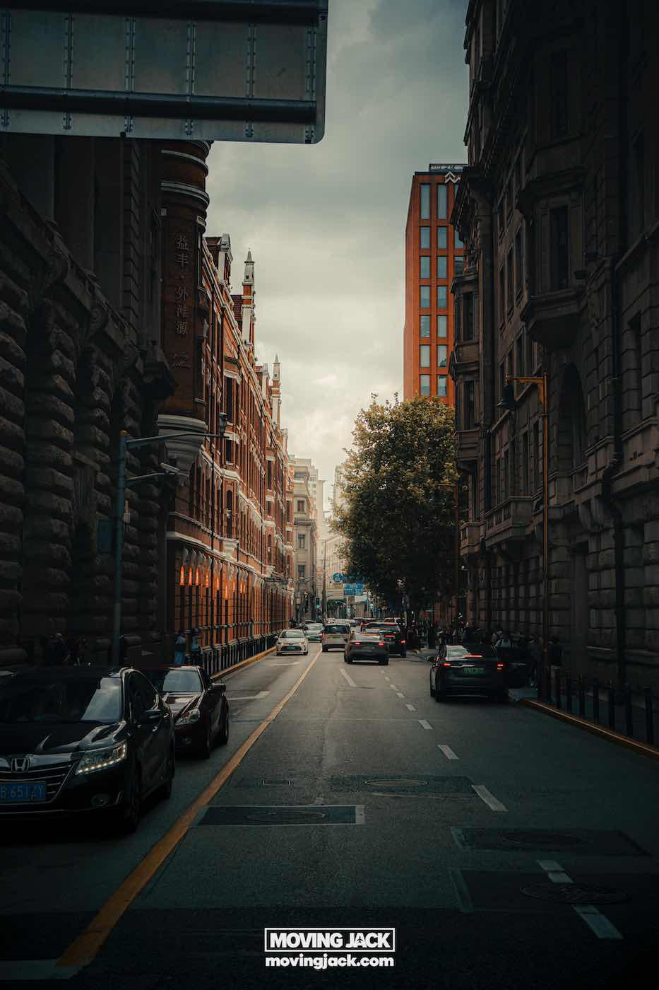 7 unieke Lightroom-tips en -trucs voor professionele kleurcorrectieresultaten 3 Lightroom-tips Een stadsstraat met historische gebouwen en geparkeerde auto's, met bewegende voertuigen en bomen zichtbaar onder een bewolkte hemel. -copyright-moving-jack.com