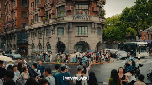 Crowded city intersection on a rainy day with people holding umbrellas and traffic; a historic building stands in the background. Discover everyday moments and things to do in shanghai. The words "moving jack" appear at the bottom center. -copyright-moving-jack. Com