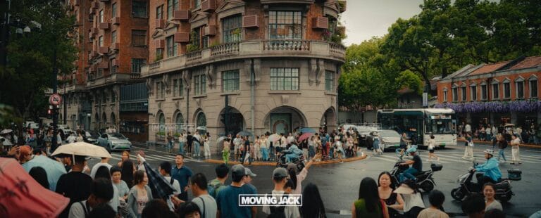 Crowded city intersection on a rainy day with people holding umbrellas and traffic; a historic building stands in the background. Discover everyday moments and things to do in shanghai. The words "moving jack" appear at the bottom center. -copyright-moving-jack. Com
