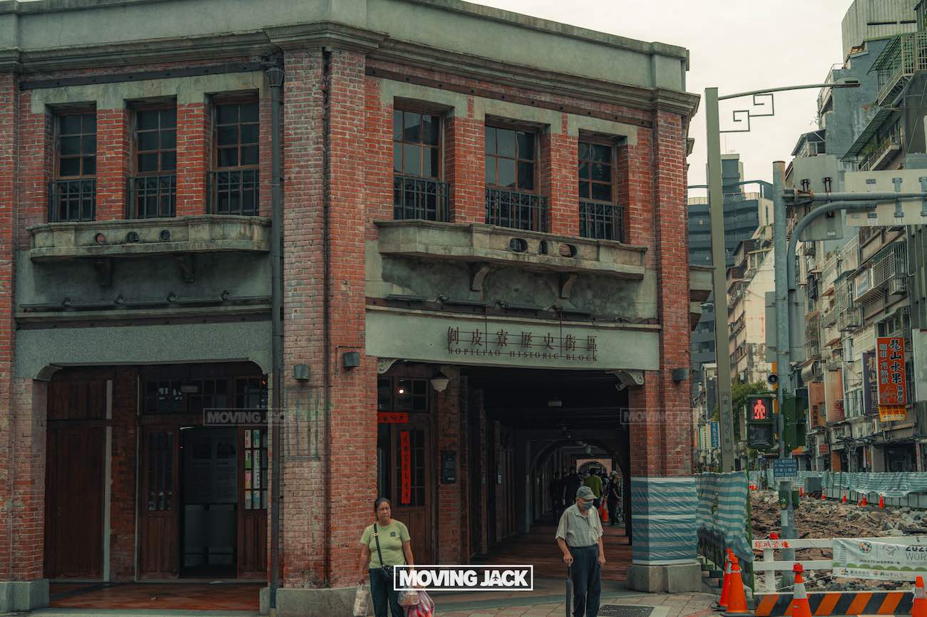20+ best things to do in taipei (by an expert) 31 things to do in taipei A historic red-brick building with arched windows stands next to a sidewalk, where two people walk past. Construction barriers and signs are visible on the right side of the street. -copyright-moving-jack. Com