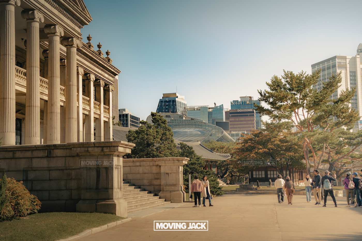 31 best free & cheap things to do in seoul (by an expert) 57 free things to do in seoul People walk near a historic building with columns and stairs, modern skyscrapers and trees in the background—a classic scene among the free things to do in seoul. The words "moving jack" are at the bottom of the image. -copyright-moving-jack. Com