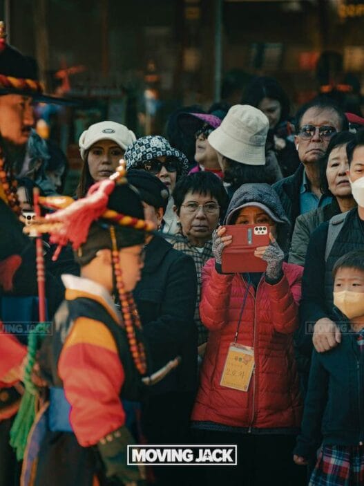 31 best free & cheap things to do in seoul (by an expert) 46 renting a car in okinawa A crowd enjoys a traditional cultural parade—one of the free things to do in seoul—with two people in colorful historical costumes. Some spectators wear masks, while another records the vibrant scene with a red phone. -copyright-moving-jack. Com