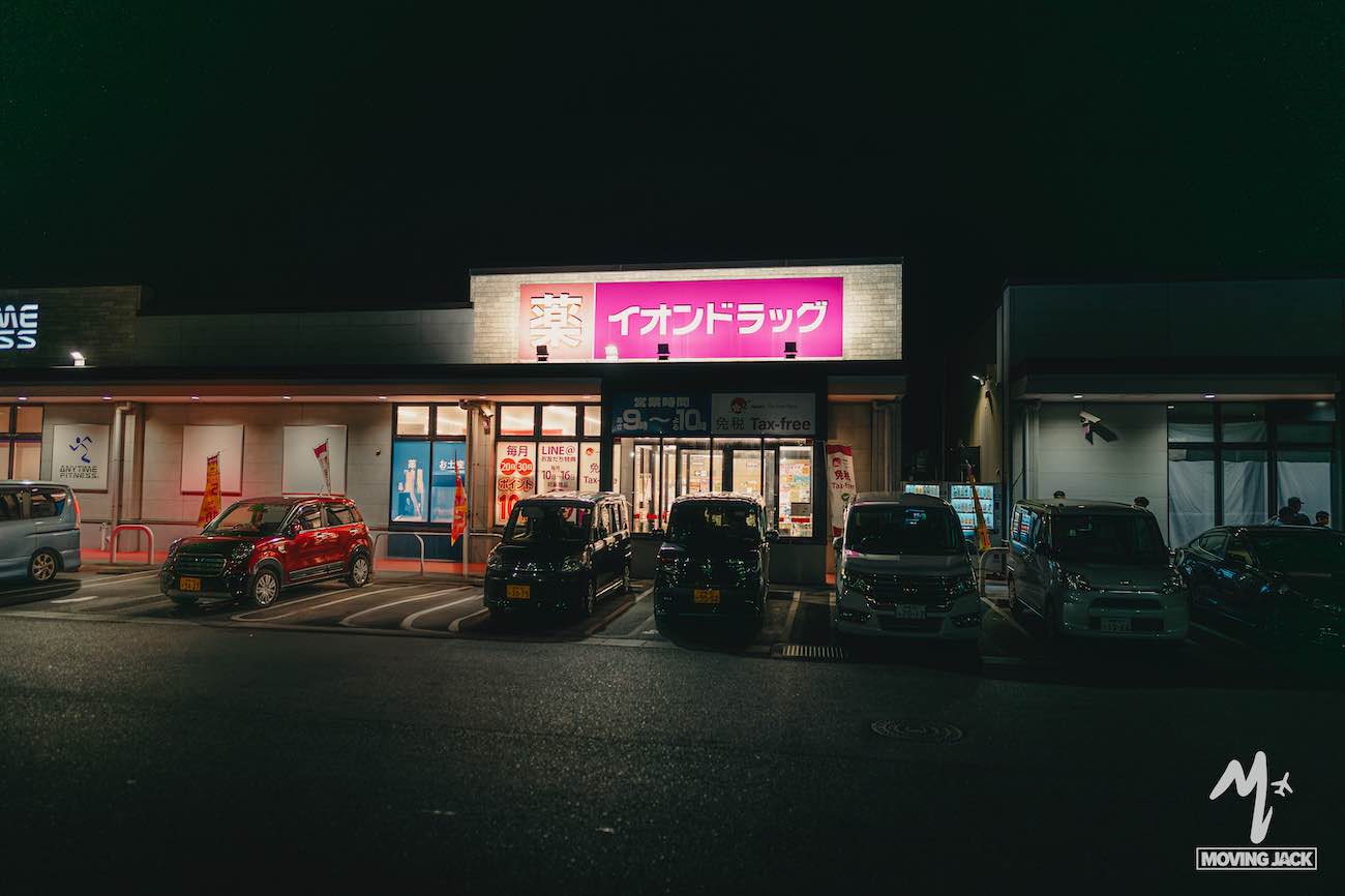 26 okinawa tips first-time visitors need to know 8 A brightly lit japanese drugstore with a pink sign is open at night, perfect for a quick stop on your okinawa itinerary. Several cars are parked in front, and the surrounding area is dark. The store sign reads "イオンドラッグ" (aeon drug). -copyright-moving-jack. Com