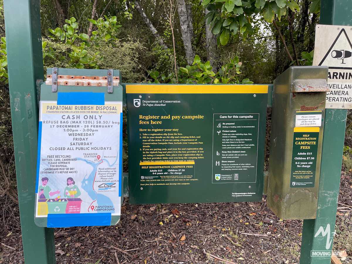 Campsite payment and rubbish disposal signs at a green information board outdoors, with instructions—perfect for those wondering, "is New Zealand by campervan worth it?.