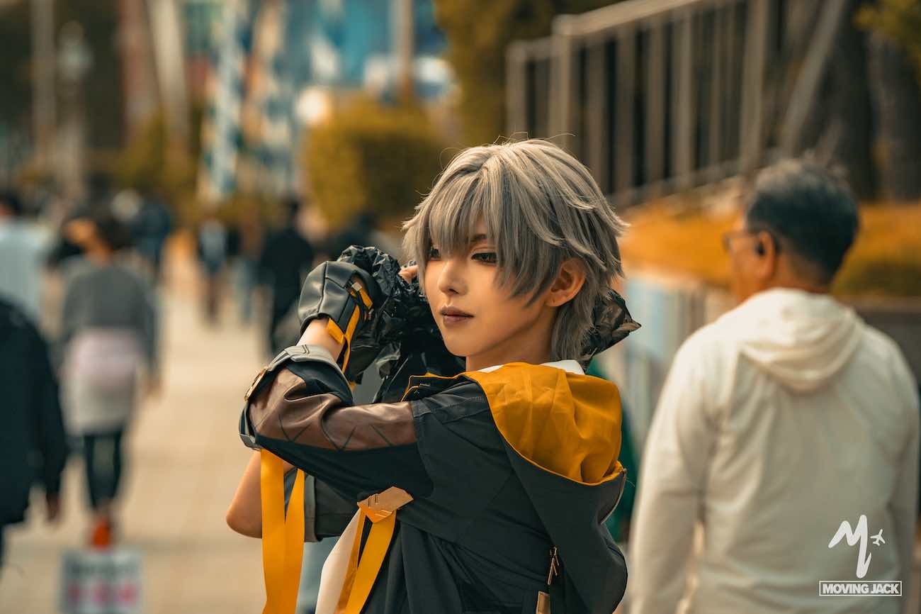 Person in detailed cosplay costume posing outdoors in vibrant Busan, with blurred people and buildings in the background—showcasing why many ask, is Busan worth visiting for events like this?.