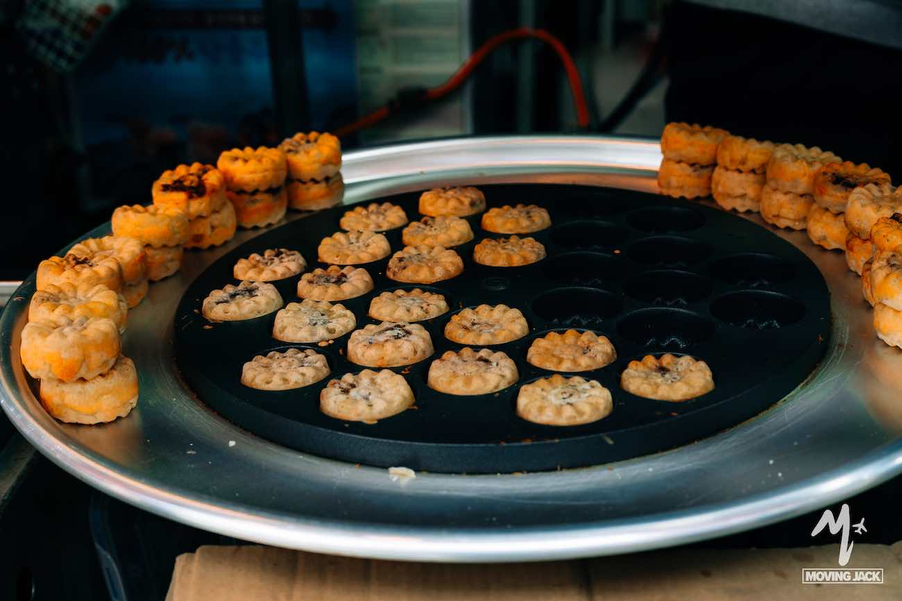 Small round pastries with chocolate chips arranged on a circular tray, some still baking in a mold—much like discovering if is Busan worth visiting, these treats promise delightful surprises in every bite.
