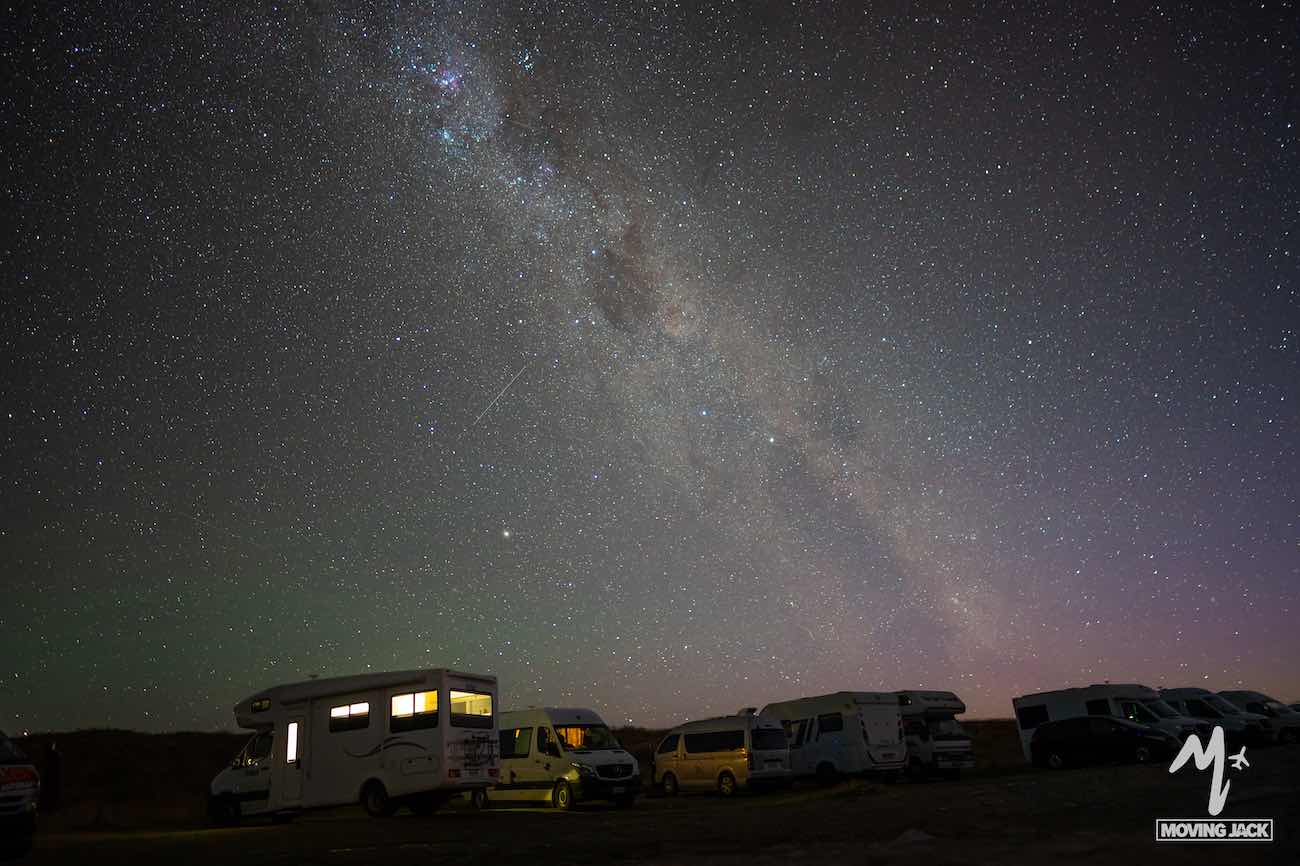 Campers parked under a starry night sky with the Milky Way galaxy above—a magical scene that makes you wonder, is New Zealand by campervan worth it? Absolutely. The views are simply unforgettable.