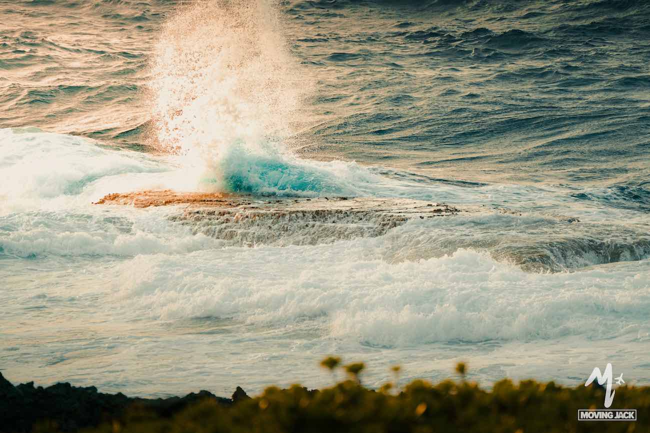 De golven van de oceaan die tegen de rotsen slaan en een grote plons vormen met wat groen op de voorgrond, roepen de serene schoonheid op van kustbestemmingen zoals Okinawa. Veel reizigers vragen zich af: is Okinawa wel veilig? De vredige kusten worden zowel door de lokale bevolking als door toeristen gewaardeerd.