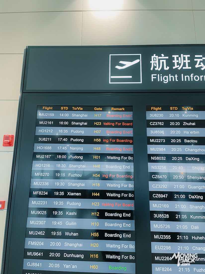 Airport flight information board at Shanghai airports showing flights, destinations, gates, and statuses like "Boarding" and "Waiting for Board.