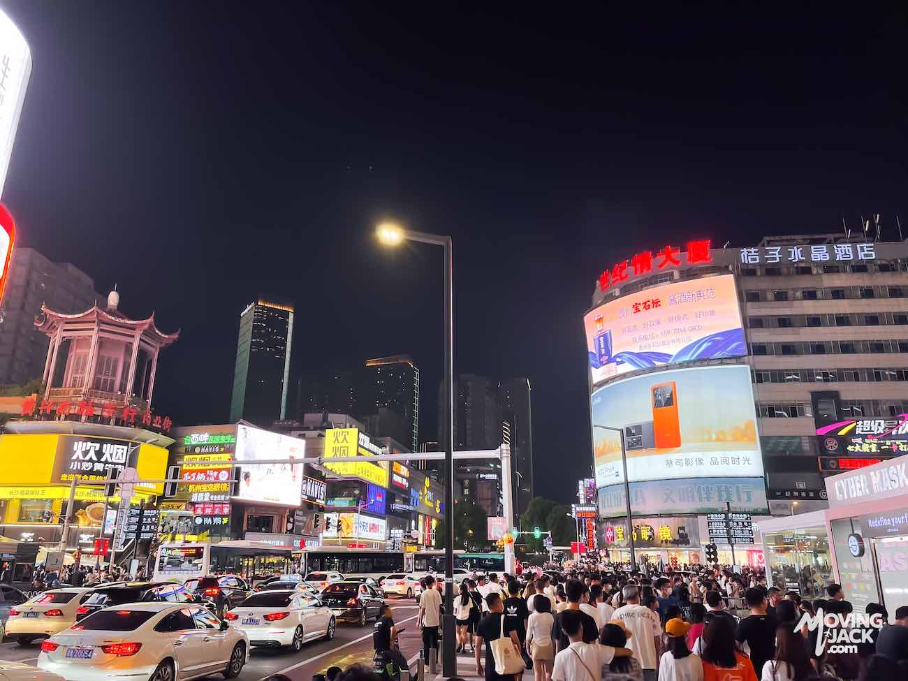 Een drukke stadsstraat 's nachts met felle neonreclames, veel mensen en hoge gebouwen op de achtergrond – perfect voor wie op zoek is naar een accommodatie in Changsha.