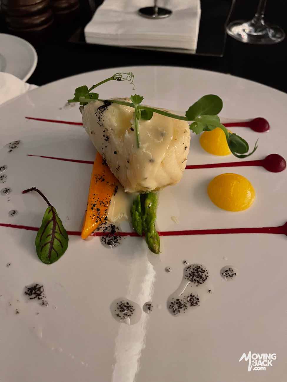 Een gastronomisch visgerecht met groenten, kleurrijke sauzen en microgroenten op een wit bord – perfect voor fijnproevers die op zoek zijn naar een accommodatie in Changsha waar ze kunnen genieten van lokale culinaire hoogstandjes.