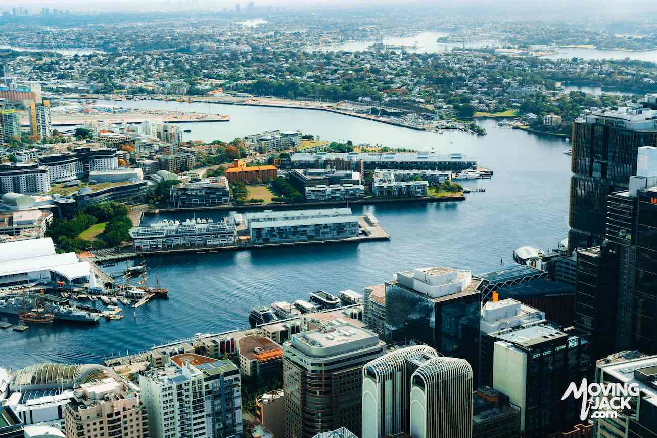 Aerial view of Sydney waterfront buildings and harbor under a bright, clear sky