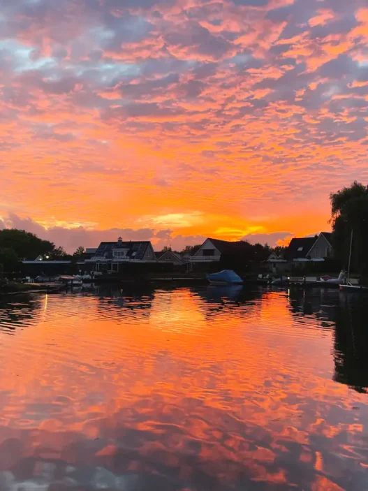 20 foto's: prachtige luchten in Nederland (Zeeland) 14 steden in Europa, top 5 steden in Europa De zonsondergang boven een kalm meer met silhouetten van huizen en bomen weerspiegelt feloranje en roze wolken, en legt zo de prachtige lucht boven Nederland vast.